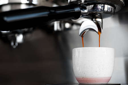 Hot aromatic coffee flows into the Cup from the coffee machine. Side view with space for your textの写真素材