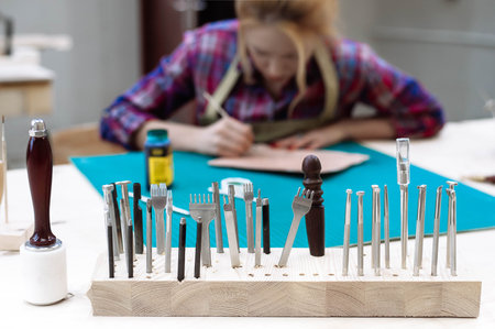 A set of tools for finishing the leather craft stand in a row against the background of a working...