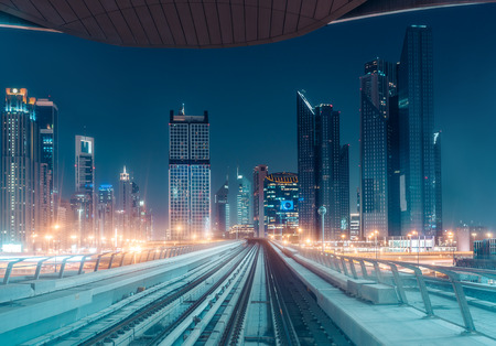 Illuminated modern architecture of Dubai's downtown by night seen from a metro train.の写真素材