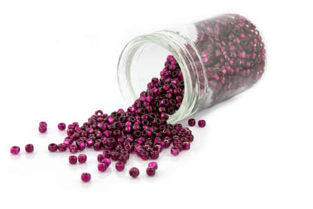 Cranberry-colored beads falling from jarの写真素材