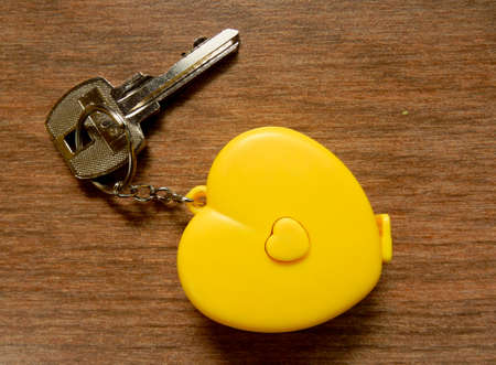 yellow heart keychain with metal key on wood backgroundの写真素材