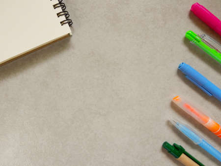 note book with many color of pen on gray background (note space)の写真素材
