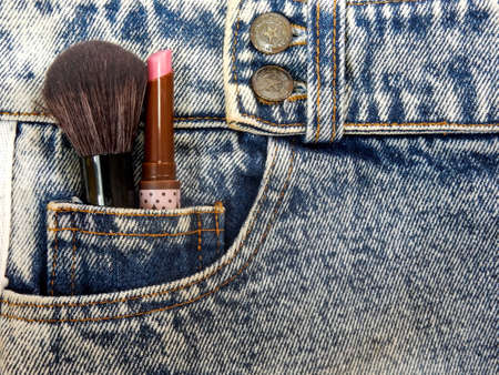 blue faded jeans  closeup with cosmetic equipment is brush and lipstick in front pocketの写真素材