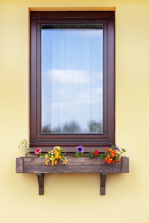 Brown window with flowers in hanging flower potの写真素材