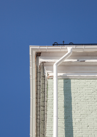 New rain gutter on a brick wall against blue skyの写真素材