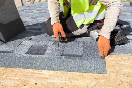 Worker cuts shingles witk scissorsの写真素材