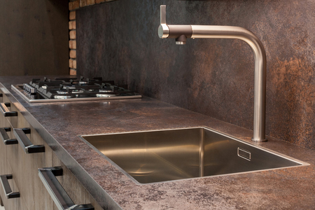 Modern designer chrome water tap over stainless steel kitchen sink.の写真素材