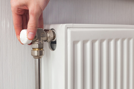 Radiator adjustment closeup. Man's hand adjusting radiator temperature.の写真素材