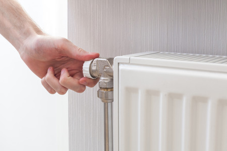 Radiator adjustment closeup. Man's hand adjusting radiator temperature.の写真素材