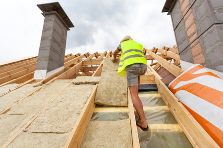 Roofer builder worker installing roof insulation material (rockwool) on new house under constructionの写真素材