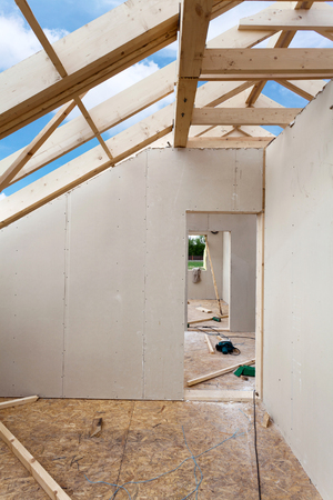 Attic room under construction with gypsum plaster boards. Roofing Construction Indoor. Wooden Roof Frame House Construction.の写真素材