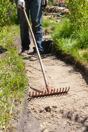 Worker making a walk path in garden decorated with wooden stumpsの写真素材