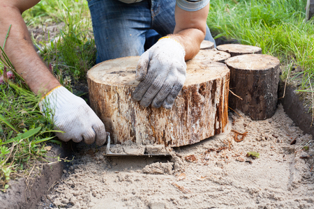 Worker making a walk path in garden decorated with wooden stumpsの写真素材