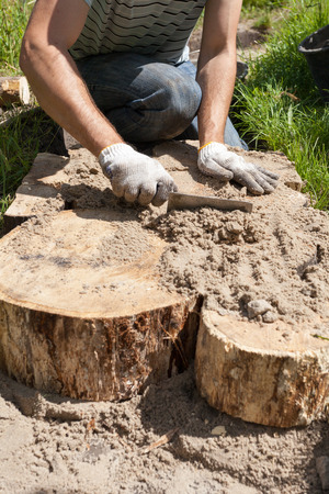 Worker making a walk path in garden decorated with wooden stumpsの写真素材
