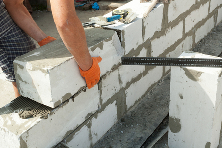 Mason aligning aerated autoclaved concrete block of constructed house wallの写真素材