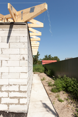 Installation of wooden beams, roof rafters at roof construction. New house made with autoclaved aerated concrete blocksの写真素材