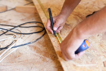 Construction work. Woodwork. Male builder marking point on hardboardの写真素材