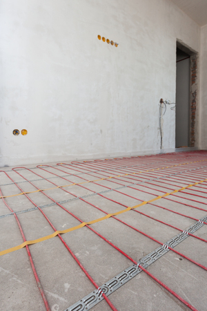 Electric floor heating system installation in new house. Closeup of  red electrical wiresの写真素材