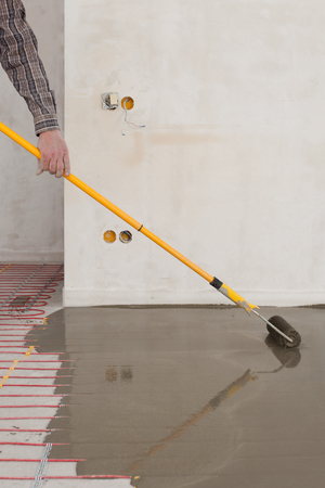 Electric floor heating system installation in new house. Roller for pouring concrete floor.の写真素材