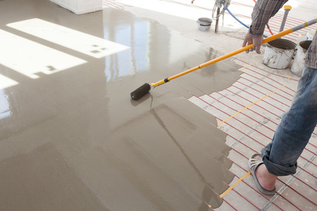 Electric floor heating system installation in new house. Roller for pouring concrete floor.の写真素材