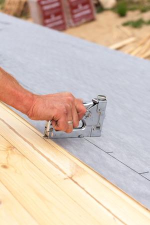 Roofer nails lining using construction stapler. Roof under constructionの写真素材
