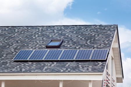 Solar water panel heating on new house roof with skylights against blue skyの写真素材