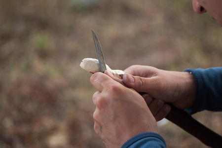 Man's hands working suit carving a wooden spoon with a knifeの写真素材