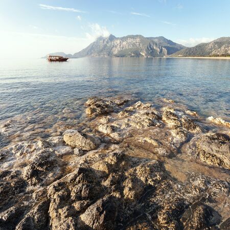 Cove in the clear sea on the background of the rocky mountainsの写真素材