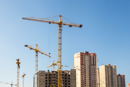 Crane and building construction site against blue skyの写真素材