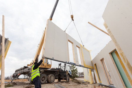 Roofer builder workers with crane installing structural Insulated Panels SIP. Building new frame energy-efficient houseの写真素材