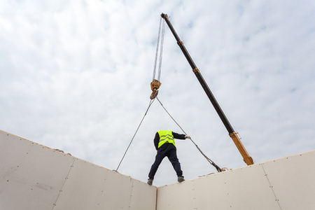 Roofer builder workers with crane installing structural Insulated Panels SIP. Building new frame energy-efficient houseの写真素材