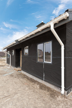 SIP panel house with new gray metal tile roof,white rain gutter and insulationの写真素材