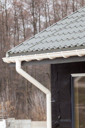 New gray metal tile roof with white rain gutter