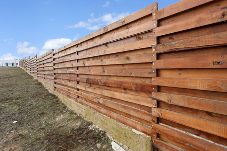 Long wooden cedar fence against blue skyの写真素材