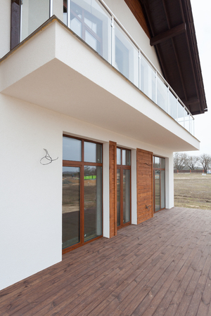 New house with white walls, wooden terrace and 
glass balconの写真素材