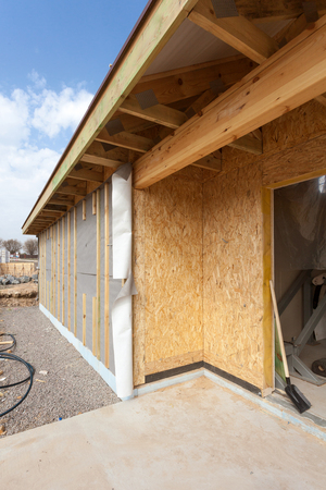 Modern frame energy efficient house under construction with membrane coverings, roof shingles and insulation materialsの写真素材