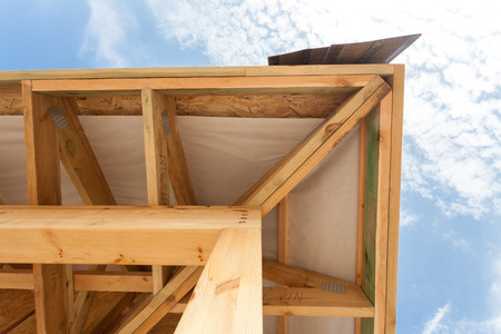 Corner of house with eaves, wooden beams and roof asphalt shinglesの写真素材