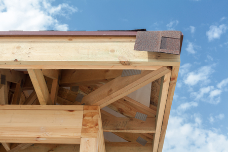 Corner of house with eaves, wooden beams and roof asphalt shinglesの写真素材