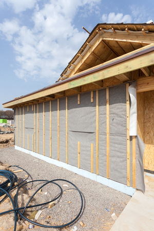 Modern frame energy efficient house under construction with membrane coverings, roof shingles and insulation materialsの写真素材