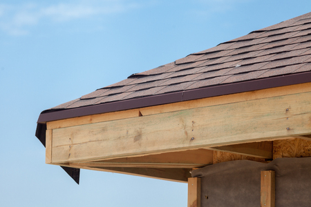 Corner of house with eaves, wooden beams and roof asphalt shinglesの写真素材