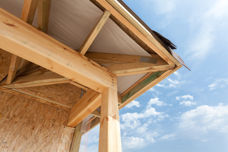 Corner of house with eaves, wooden beams and roof asphalt shinglesの写真素材