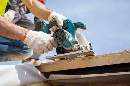 Installing a skylight. Construction Builder Worker use Circular Saw to Cut a Roof Opening for windowの写真素材