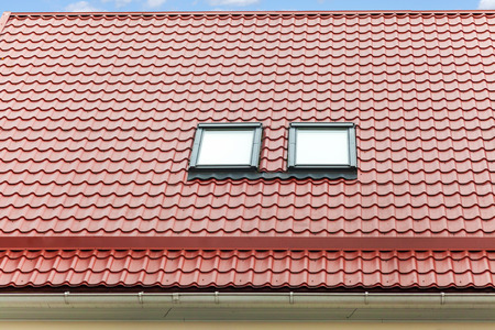 New red metal roof with skylights and rain gutterの写真素材