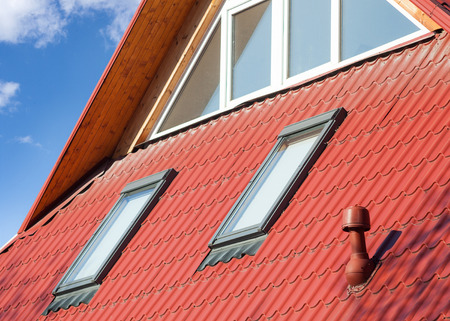 New red metal roof with windows (skylights) and ventilator for heat controlの写真素材