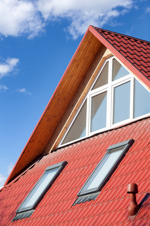 New red metal roof with attic windows (skylights) and Ventilation pipe for heat controlの写真素材
