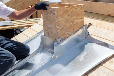 Roofer builder worker attach metal sheet to the chimneyの写真素材