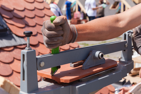 Roofer builder worker use tile cutter to create a correct size of natural red  ceramic tileの写真素材