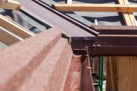 New asphalt shingle roof with brown rain gutter, wooden beams and vapour control layerの写真素材