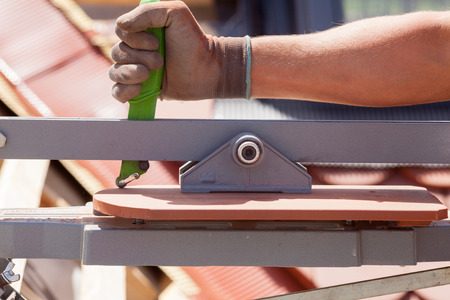 Roofer builder worker use tile cutter to create a correct size of natural red  ceramic tileの写真素材