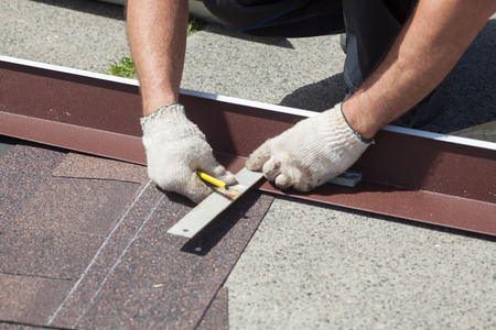 Natural roof tile instaalation. Roofer builder worker marks the distance between the seamsの写真素材